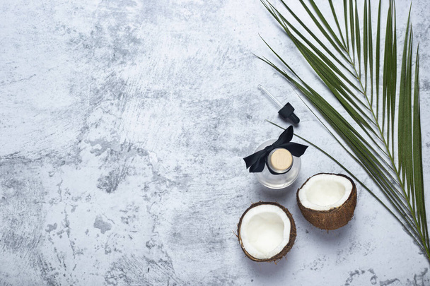 Geopende kokosnoot, fles en palmblad op betonnen ondergrond. Bovenaanzicht, vlak lay. - Foto, afbeelding