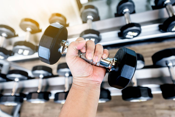 fat man Hand holding  black metal dumbbells in the gym  - Photo, image