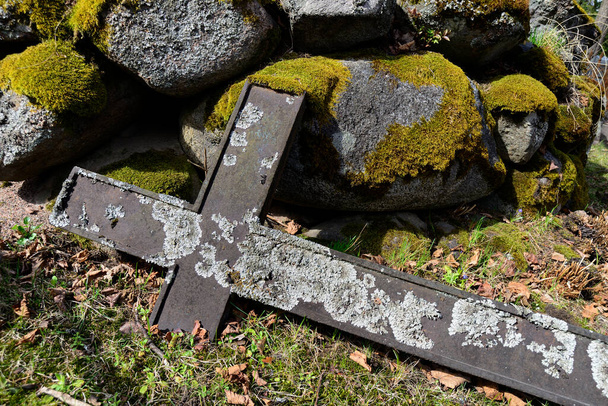 Upadły krzyż i stos pokrytych mchem kamieni na starym cmentarzu - Zdjęcie, obraz