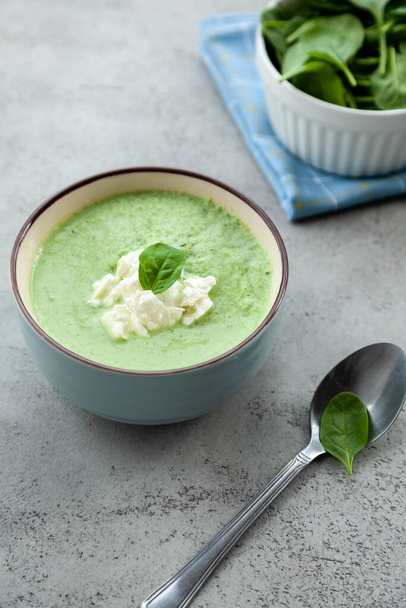 Green cream soup in a blue bowl on a stone grey table. Summer lunch or dinner. - Photo, Image