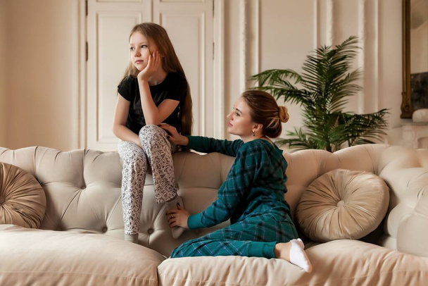 Happy pretty mother and little her cute daughter in casual clothes in living room on sofa. Concept of spending time together with kids and family lovely relationships. Copy space for site - Foto, immagini