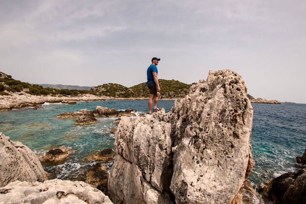man stands on large stone on the seashore against the backdrop of landscape - 写真・画像