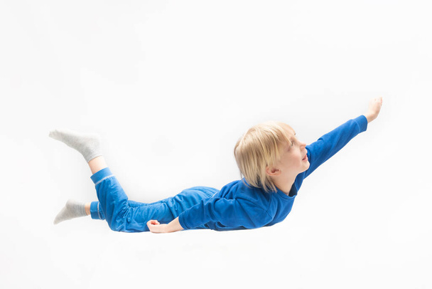 Happy little boy flying like superman. Dreaming. White background - Photo, image