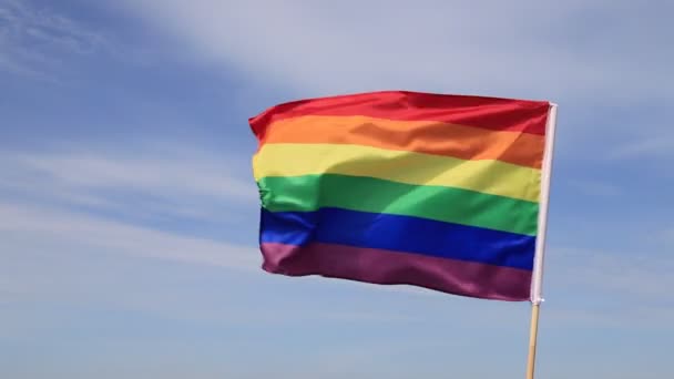 Mavi gökyüzünde gey gökkuşağı bayrağı sallıyor. Lezbiyen, gey, biseksüel, transseksüel LGBT topluluğunun parlak bayrağı. - Video, Çekim