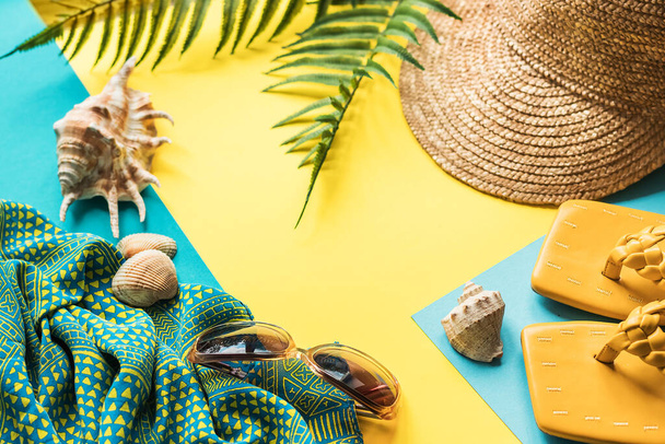 Яркий летний фон с пляжными аксессуарами. Пляжные тапочки, солнцезащитные очки, соломенная шляпа и ракушки. Квартира с копировальным пространством. - Фото, изображение