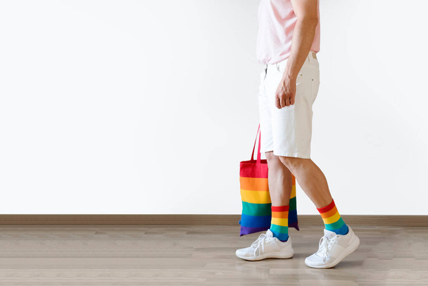 Unrecognizable young man posing dressed in socks and rainbow bag. Concept of freedom, LGBTQ+. Copy space - Foto, afbeelding