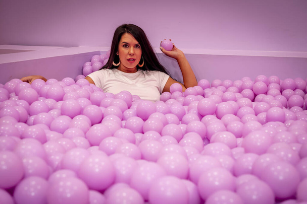 A beautiful asian model plays in a colorful room with a huge amount of plastic balls - Fotografie, Obrázek