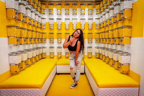 A beautiful asian model poses in a room full of gum ball machines  - Photo, Image