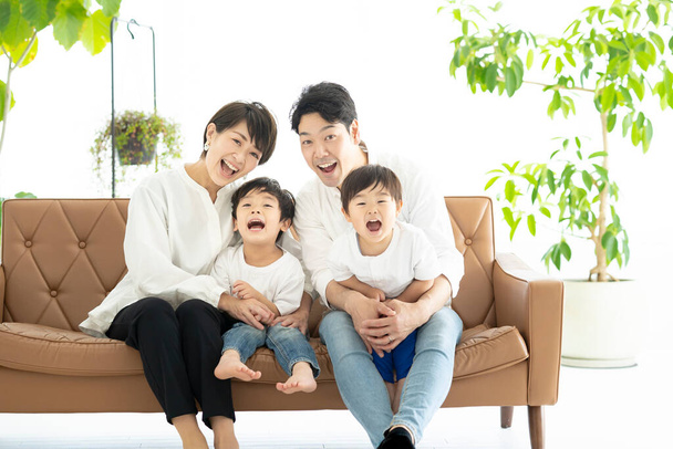 Asian family frolicking on the couch  - Valokuva, kuva