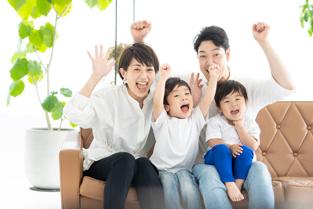 Image of parents and 2 boys watching TV with their hands raised  - Photo, Image
