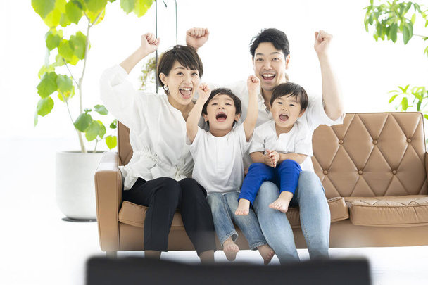 Bild von Eltern und 2 Jungen, die mit erhobenen Händen fernsehen  - Foto, Bild
