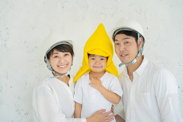 Asian boy wearing disaster prevention hoods and parents wearing helmets  - Photo, Image
