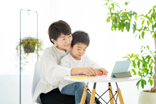 Madre e figlio che fanno origami mentre guardano un tablet PC - Foto, immagini