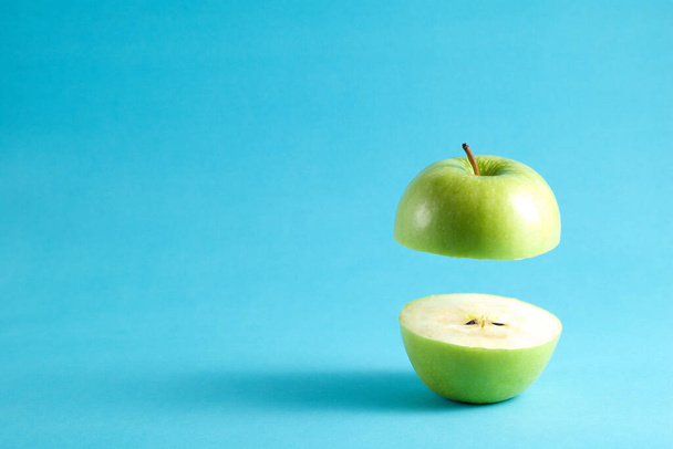 Świeże zielone jabłko z półlatającym na niebieskim tle. Latające zielone jabłko z pustą kopią miejsca na tekst. - Zdjęcie, obraz