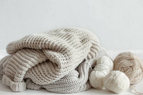 Knitted warm sweaters in pastel colors and skeins of thread close up. - Fotó, kép