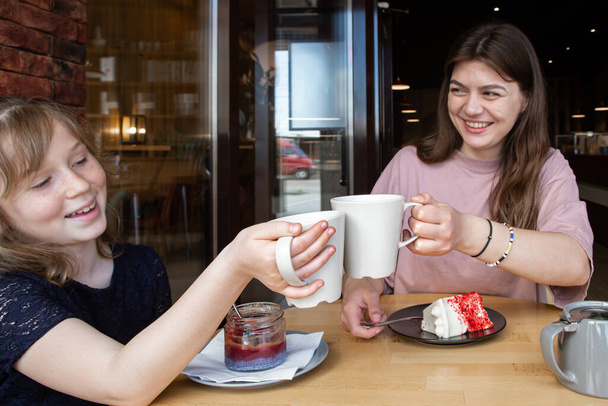 カフェで二人の女の子はお茶を飲み、デザートに自分自身を扱う. - 写真・画像