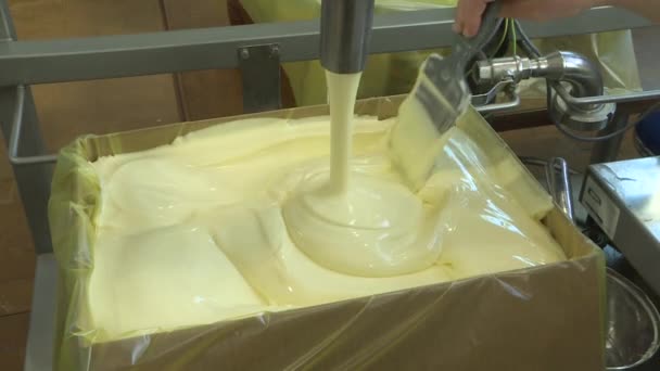 Le beurre est versé dans une boîte à la crémerie. Gros plan d'un tourbillon de crème liquide fondue. - Séquence, vidéo