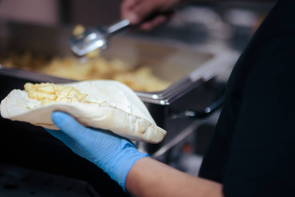 Professional Cook Putting French Fries in a Pita Wrap  - Foto, Imagen