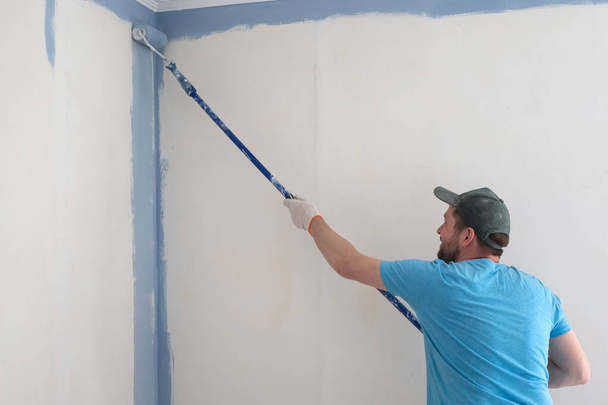 Εργαζόμενος ζωγραφική τοίχους με κύλινδρο κατά τη διάρκεια της επίπεδης ανακαίνισης - Φωτογραφία, εικόνα