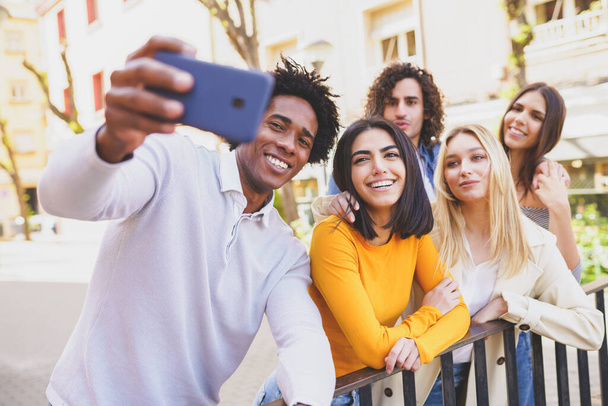 Groupe multi-ethnique d'amis prenant un selfie dans la rue avec un smartphone. - Photo, image