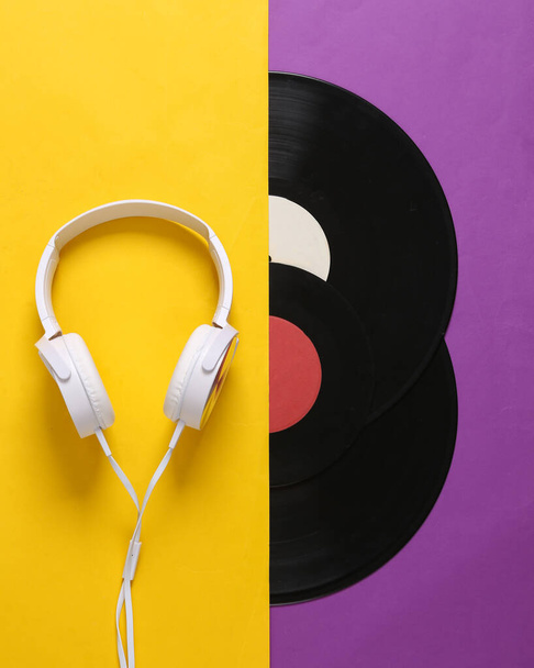 Stereo koptelefoon en vinyl platen op gele paarse achtergrond. 80-er jaren. Plat gelegd. Bovenaanzicht - Foto, afbeelding