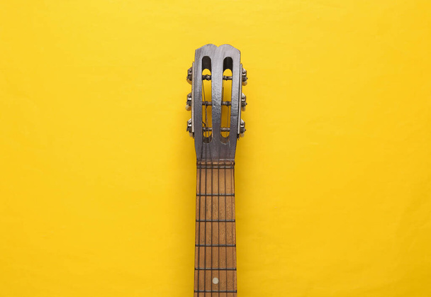 Cuello de guitarra acústica sobre fondo amarillo. Concepto musical. Minimalismo. Vista superior. Puesta plana - Foto, Imagen