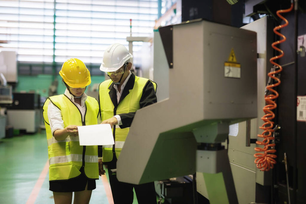 工場アジアの検査官とマネージャーは、 CNC自動旋盤機械ロボット技術マシンの内部監査のための紙の製造モデルを議論またはチェックします。業界向け品質保証(QA). - 写真・画像