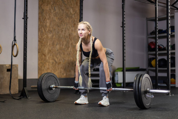 Mulher muscular realiza deadlift com peso no moderno ginásio funcional - Foto, Imagem