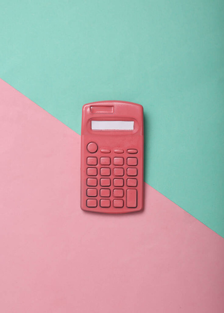 Roze rekenmachine op roze blauwe achtergrond. Minimalisme. Creatieve indeling. Bovenaanzicht. Vlakke plaat - Foto, afbeelding