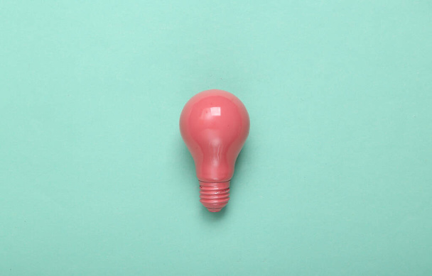 Pink light bulb on mint green background. Minimalism. Creative layout. Fresh idea. Top view. Flat lay - Фото, зображення