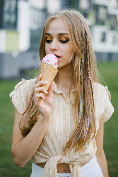 Young beautiful woman eats ice cream on a city walk on a sunny summer day on vacation - Fotoğraf, Görsel