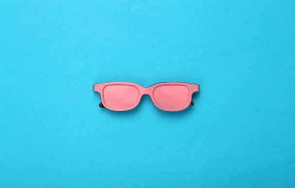 Gafas de sol rosadas sobre fondo azul. Vista superior. Acostado. Arte conceptual. Minimalismo  - Foto, Imagen