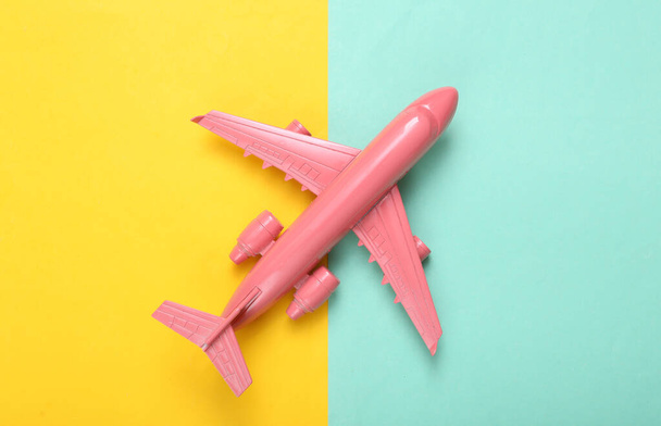 Minimalny układ podróży. Różowy samolot na niebieskim żółtym tle. Leżeć płasko. Widok z góry - Zdjęcie, obraz