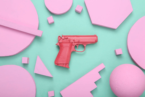 Creatief minimale indeling. Roze pistool met verschillende geometrische vormen op mintblauwe achtergrond. Minimalisme. Concept kunst. Plat gelegd. Bovenaanzicht. - Foto, afbeelding