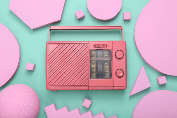 創造的な音楽レイアウト。ミントブルーの背景に異なる幾何学的な形状のピンクのアナログラジオ受信機。ミニマリズム。コンセプトアート。平置きだ。トップ表示. - 写真・画像