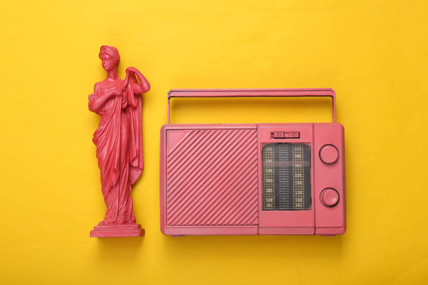 Kreatív zenei elrendezés. Rózsaszín antik görög múzsa szobor rádióvevővel sárga háttérrel. Inspiráció. Minimalizmus. Lapos fekvés. Felülnézet. - Fotó, kép