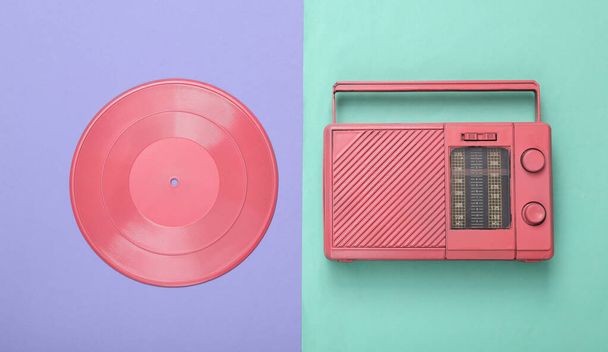 Récepteur radio rose cool et disque vinyle sur fond bleu pourpre. Concept musical minimal. Vue de dessus. Pose plate - Photo, image
