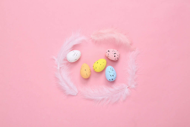 Easter composition of colored eggs and feathers on a pink background. Top view. Flat lay - Φωτογραφία, εικόνα