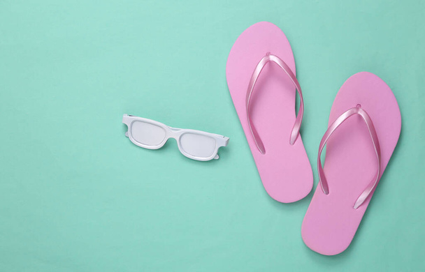 Minimalism travel layout. Flip-flops and white sunglasses on mint blue background. Top view. Flat lay - Photo, Image