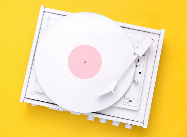 Draaitafel vinyl platenspeler op gele achtergrond. Geluidstechnologie voor DJ om muziek te mixen en af te spelen. Witte vinylplaat. Minimalisme. Plat gelegd. Bovenaanzicht. - Foto, afbeelding