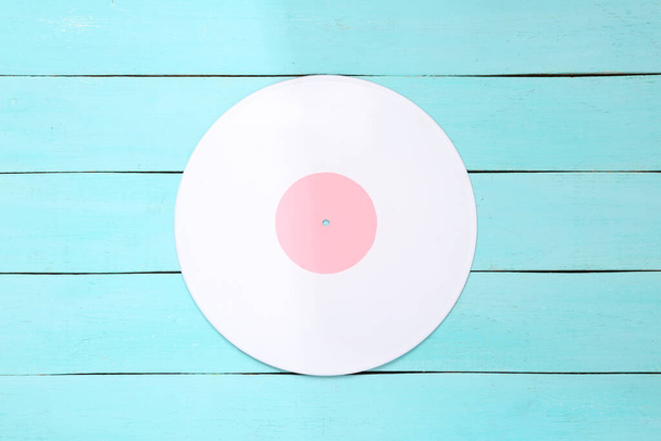 Music creative layout. White vinyl record on blue wooden background. Top view. Flat lay - Photo, Image
