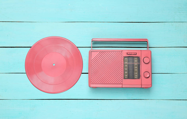 Μουσική δημιουργική διάταξη. Ροζ Vinyl εγγραφή και ραδιόφωνο δέκτη σε μπλε ξύλινο φόντο. Μινιμαλισμός. Στο πάνω μέρος. Επίπεδη - Φωτογραφία, εικόνα