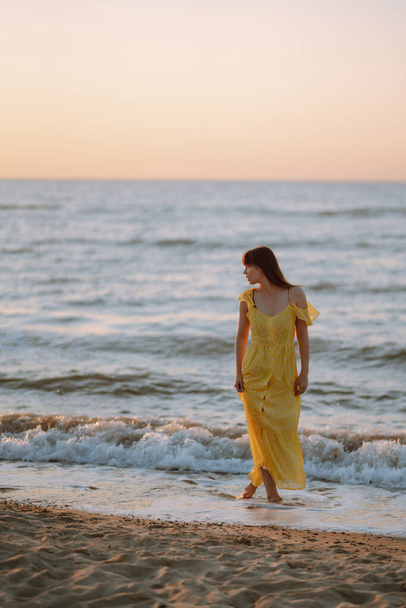 Young woman enjoying beautiful sunset on the beach. Feminine, attractive and sensual silhouette. Travel, weekend, relax and lifestyle concept. - 写真・画像