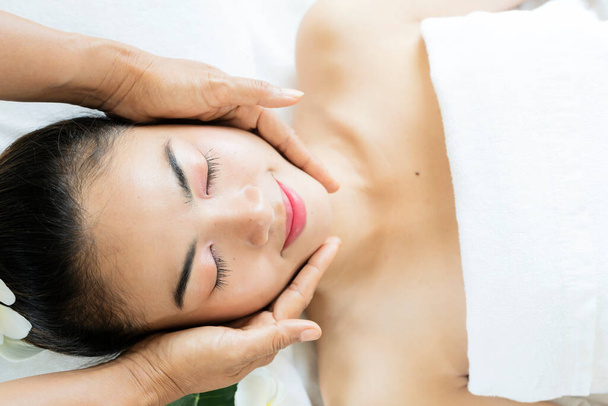 portrait of young beautiful woman in spa environment, wellness, beauty and relaxation concept - beautiful young woman lying with closed eyes and having face and head massage at spa - Φωτογραφία, εικόνα