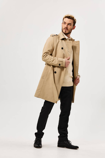 handsome man in beige coat autumn style studio full growth side view - Photo, Image