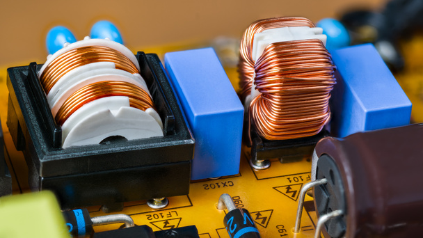 Close-up of toroidal and cylindrical coil on yellow printed circuit board. Electronic inductors with copper wire. Switch-mode power supply unit with transformers, capacitors and diodes on PCB detail. - Zdjęcie, obraz