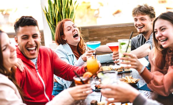 Freunde stoßen nach Feierabend im Open-Air-Bar-Restaurant auf bunte Drinks an - Life-Style-Konzept mit Menschen, die bei Happy Hour auf der Terrassenparty gemeinsam Cocktails trinken - Foto, Bild