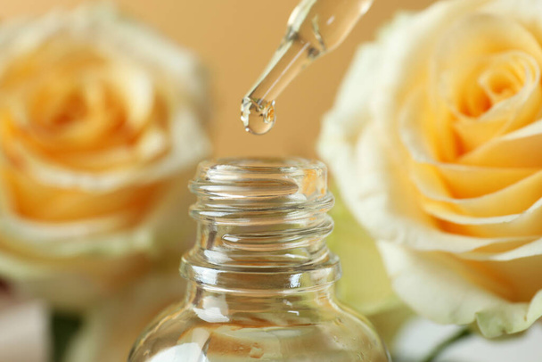 Rose essential oil falling from glass dropper into a bottle - Foto, Imagen