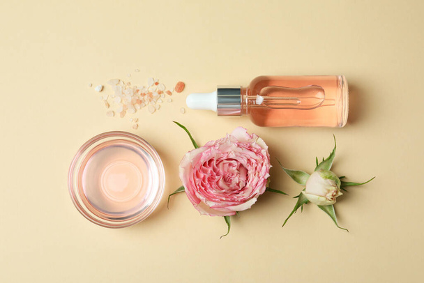 Concetto di cura della pelle con olio essenziale di rosa su sfondo beige, vista dall'alto - Foto, immagini