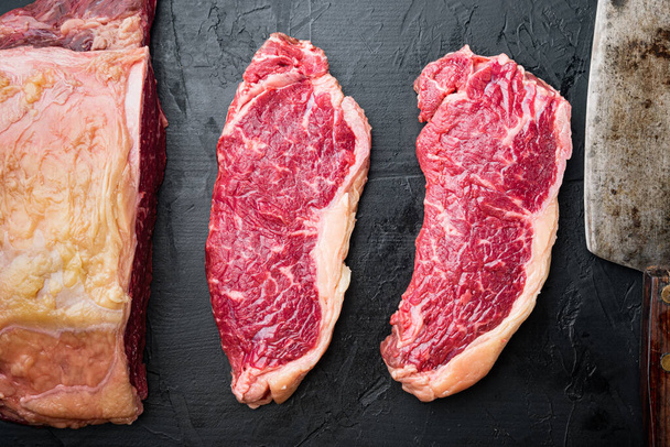 Veiny steak, gemarmerd rundvlees rauw vlees, op zwarte achtergrond, bovenaanzicht - Foto, afbeelding
